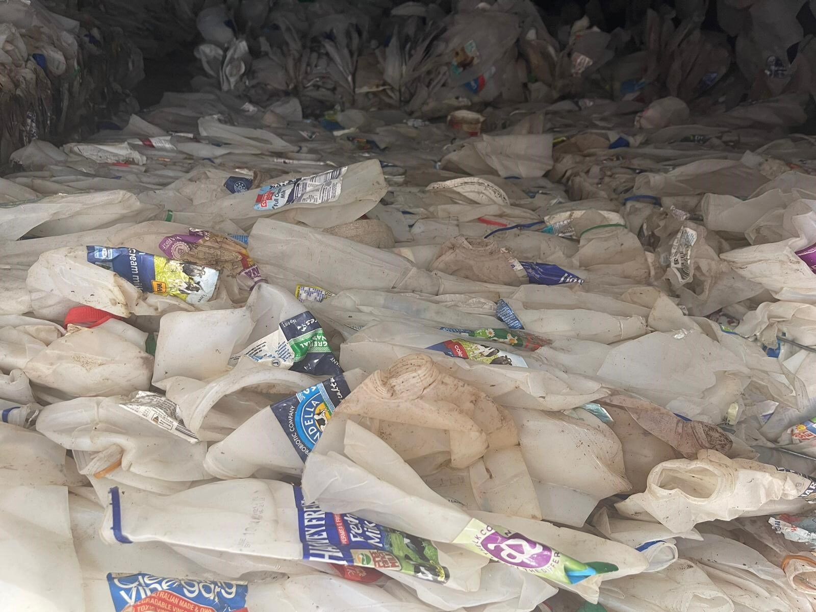 A pile of trash bags and cans in the middle of a floor.